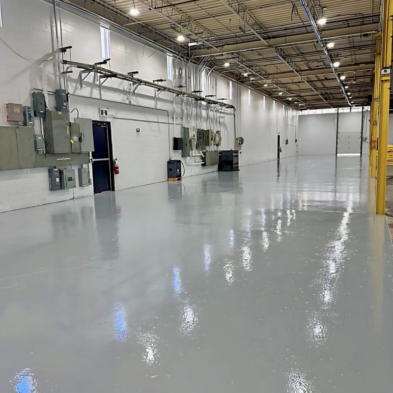 Large industrial warehouse with newly painted glossy gray epoxy floor.