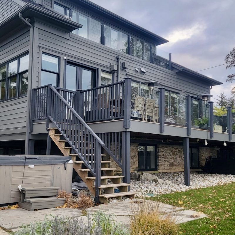 Modern dark gray house with freshly painted exterior and large glass windows.