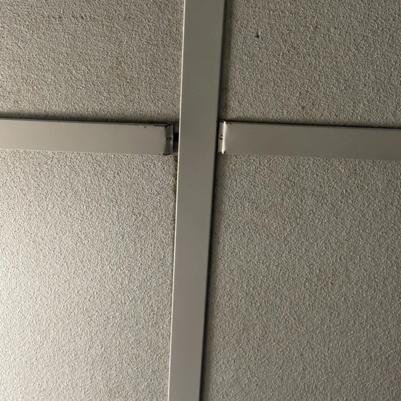 Close-up view of a ceiling grid showing a misaligned metal frame section.