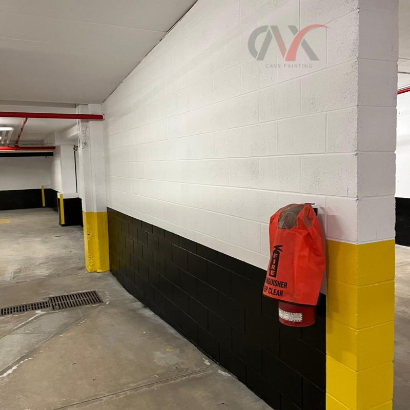 Parking garage wall freshly painted white, black, and yellow with fire gear nearby.
