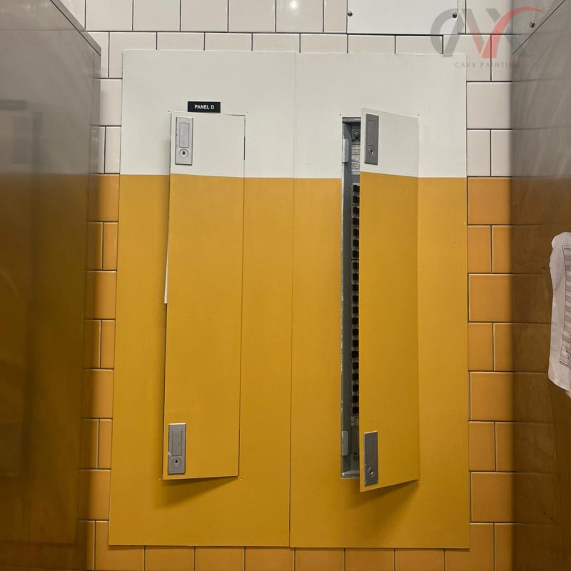 Yellow and white painted electrical panel doors in a tiled interior space.