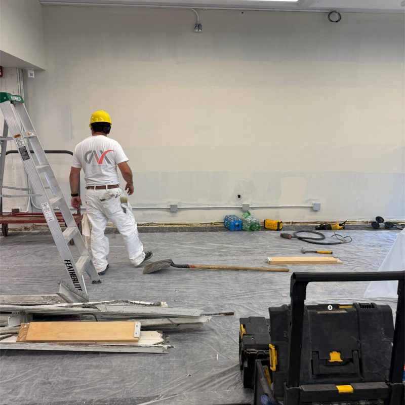 Painter applying wall coating in a workspace under renovation.