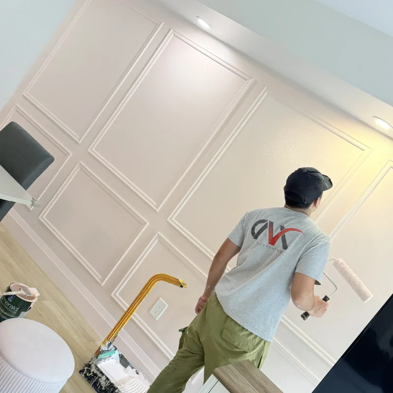 Worker painting a decorative interior wall with a roller in a modern room.